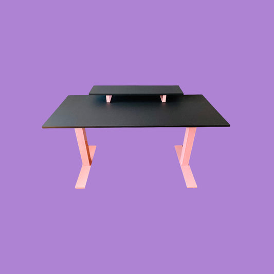 Matte black desk with a pink desk frame and a matte black monitor riser with pink feet.